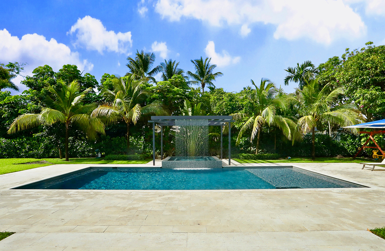 A pool with a waterfall and palm trees in the background.